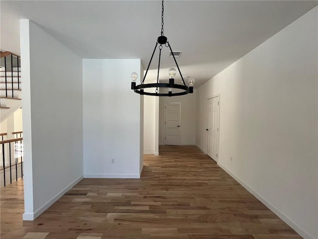 unfurnished dining area featuring a chandelier and dark wood-type flooring