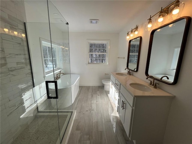 full bathroom featuring plus walk in shower, wood-type flooring, vanity, and toilet