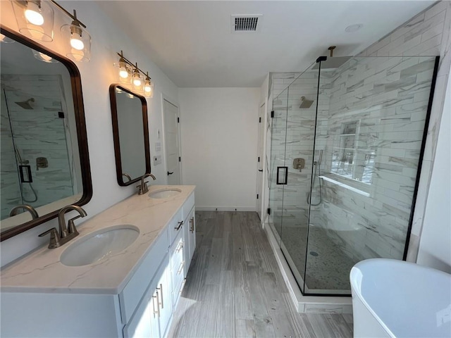 bathroom featuring hardwood / wood-style floors, vanity, and plus walk in shower