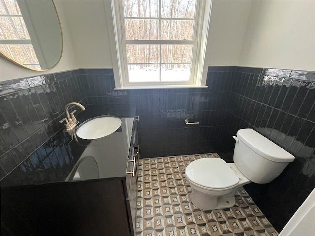 bathroom with vanity, toilet, and tile walls