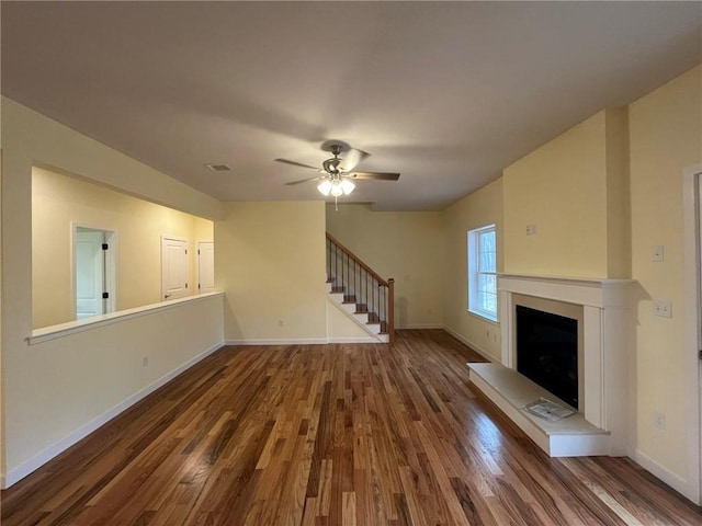 unfurnished living room featuring ceiling fan and dark hardwood / wood-style flooring