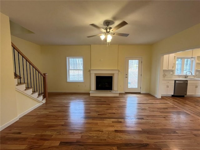 unfurnished living room featuring ceiling fan, a healthy amount of sunlight, dark hardwood / wood-style flooring, and sink