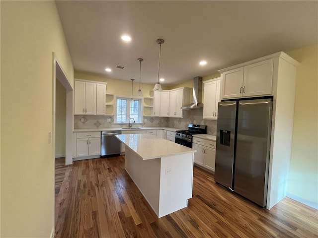 kitchen featuring stainless steel appliances, white cabinetry, a kitchen island, and wall chimney exhaust hood