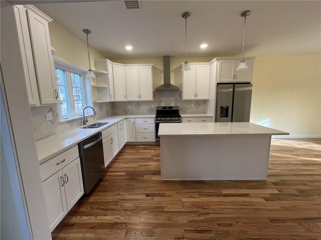 kitchen with a kitchen island, sink, white cabinets, stainless steel appliances, and wall chimney range hood