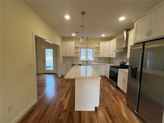 kitchen featuring sink, white cabinetry, a center island, appliances with stainless steel finishes, and wall chimney range hood