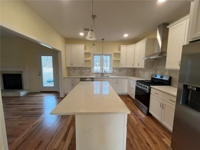 kitchen featuring wall chimney exhaust hood, sink, a center island, stainless steel appliances, and white cabinets