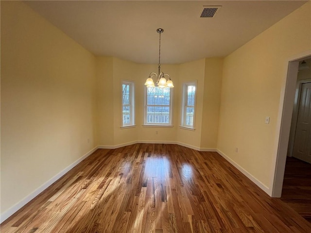 unfurnished dining area featuring wood-type flooring and a notable chandelier