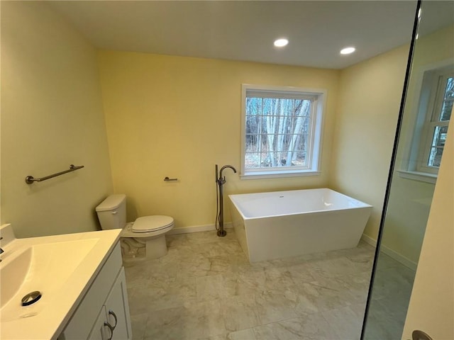 bathroom featuring vanity, a bath, and toilet