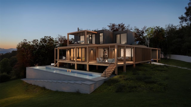 back house at dusk featuring a pool side deck