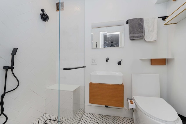 bathroom featuring tile patterned flooring, a tile shower, vanity, and toilet