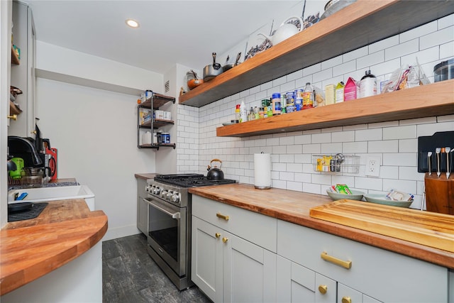 kitchen featuring dark wood finished floors, open shelves, high end stove, butcher block counters, and tasteful backsplash
