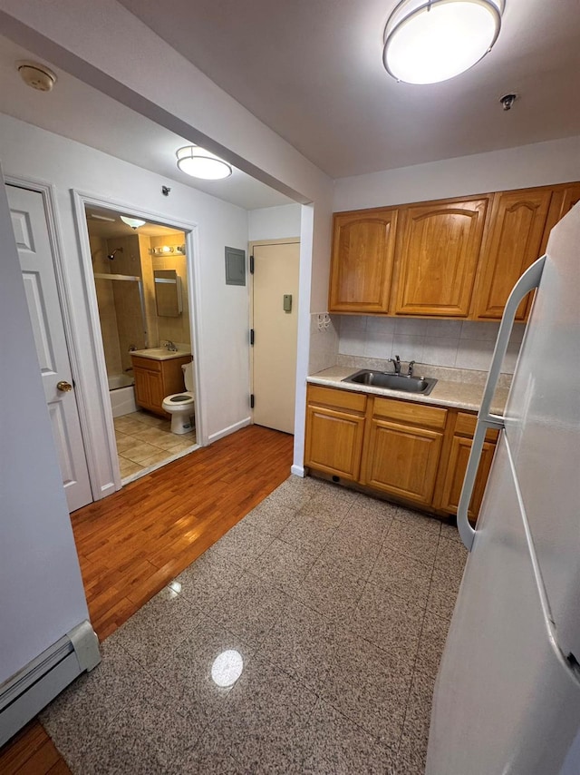 kitchen featuring backsplash, a baseboard radiator, white fridge, and sink