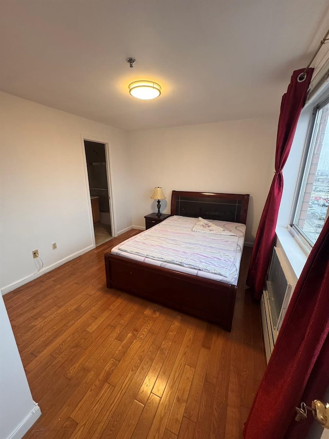 bedroom featuring hardwood / wood-style floors and a baseboard heating unit