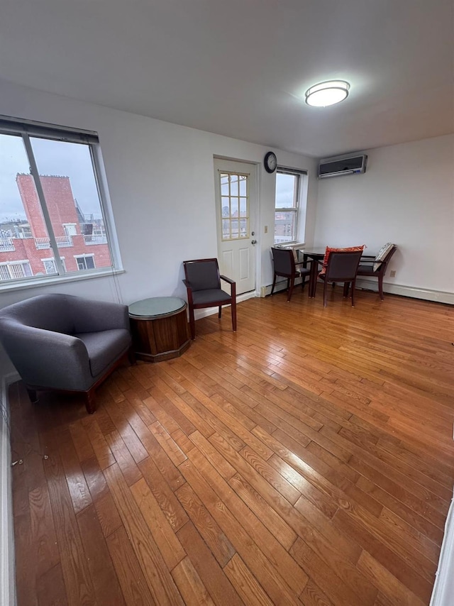 sitting room featuring a wall mounted air conditioner and hardwood / wood-style floors