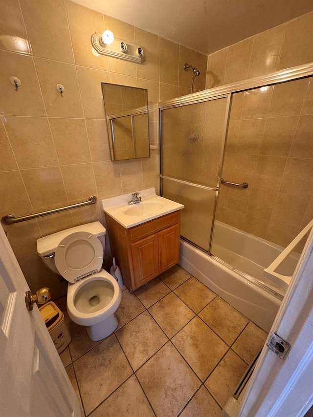 full bathroom with tile patterned floors, vanity, tile walls, enclosed tub / shower combo, and toilet