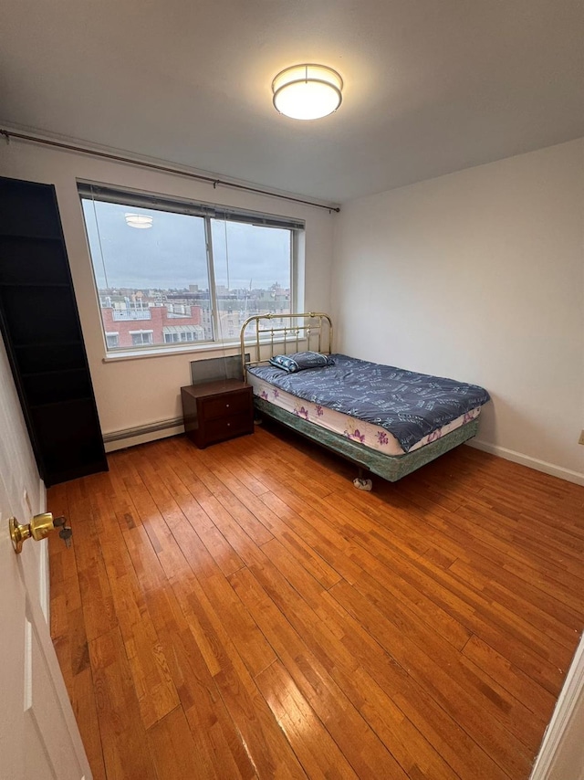 unfurnished bedroom with baseboard heating and wood-type flooring