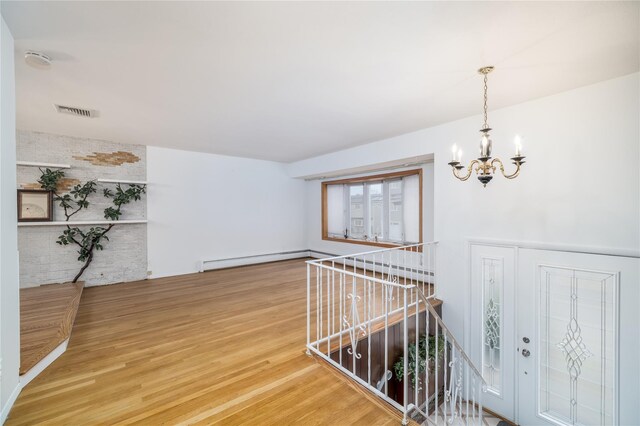 corridor featuring baseboard heating, wood-type flooring, and a notable chandelier