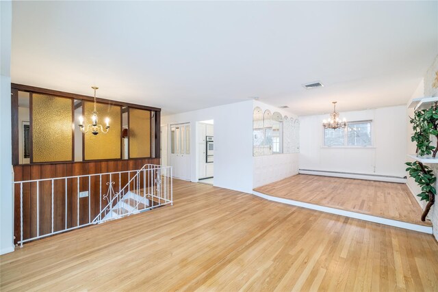 spare room featuring hardwood / wood-style flooring, a chandelier, and a baseboard heating unit