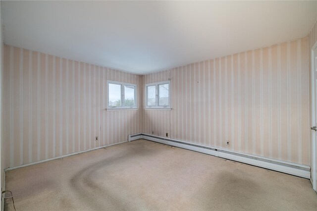 carpeted spare room featuring a baseboard heating unit