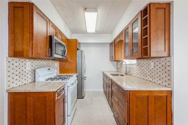 kitchen with backsplash, light stone counters, sink, and stainless steel appliances