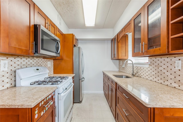 kitchen with light stone counters, sink, appliances with stainless steel finishes, and tasteful backsplash