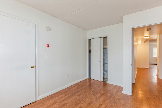 unfurnished bedroom featuring light hardwood / wood-style floors and baseboard heating