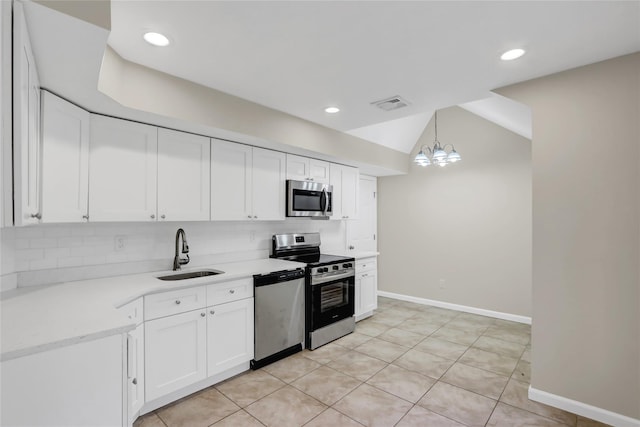 kitchen with appliances with stainless steel finishes, sink, a chandelier, white cabinetry, and hanging light fixtures