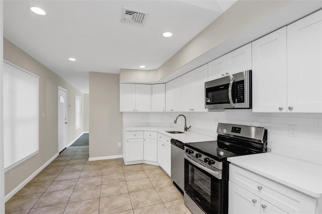 kitchen featuring stainless steel appliances, white cabinetry, tasteful backsplash, and light tile patterned flooring