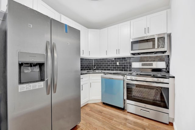 kitchen featuring white cabinets, sink, decorative backsplash, light hardwood / wood-style floors, and stainless steel appliances