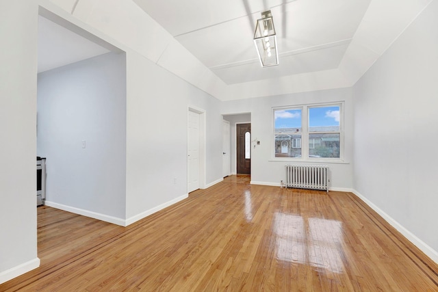 spare room with radiator heating unit and wood-type flooring