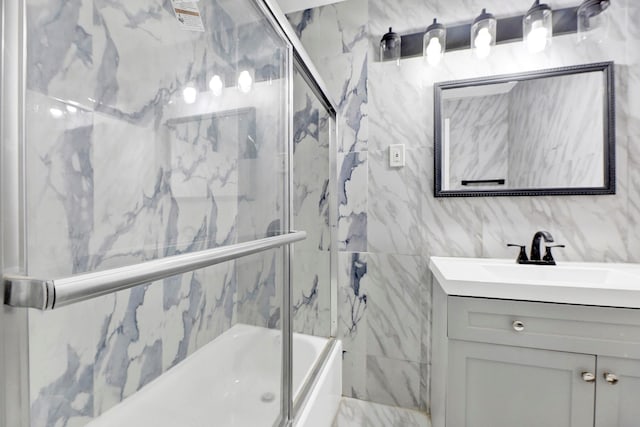 bathroom with vanity, tile walls, and combined bath / shower with glass door