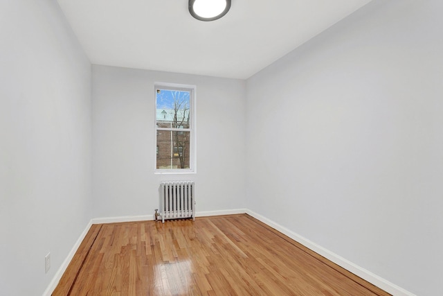 unfurnished room featuring radiator and hardwood / wood-style flooring