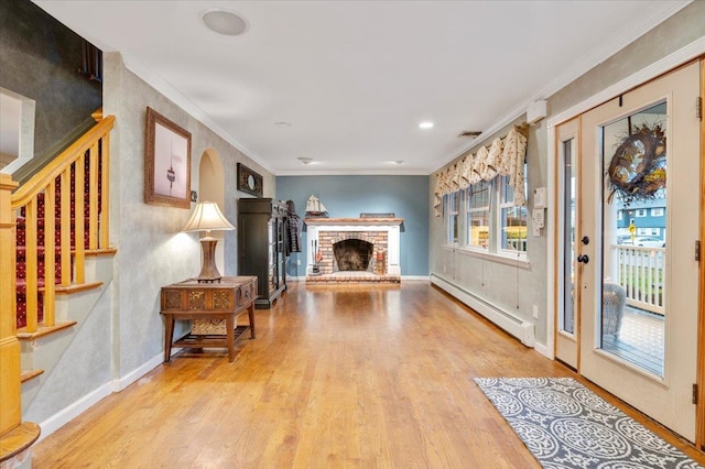 living room with a brick fireplace, ornamental molding, light wood-type flooring, and a baseboard heating unit