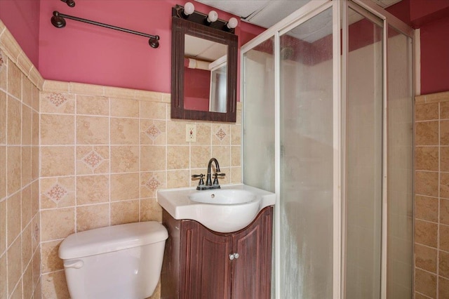 bathroom featuring vanity, toilet, walk in shower, and tile walls