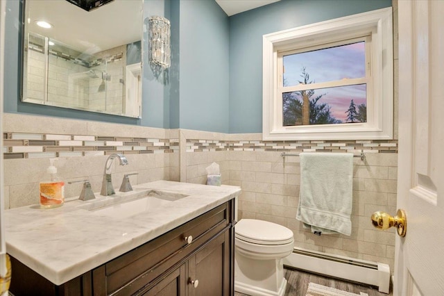 bathroom with vanity, a baseboard heating unit, tile walls, toilet, and a shower with shower door