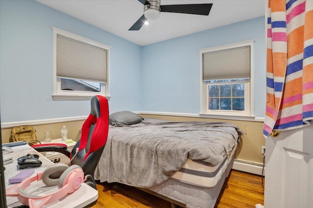 bedroom with ceiling fan, light hardwood / wood-style flooring, and a baseboard radiator