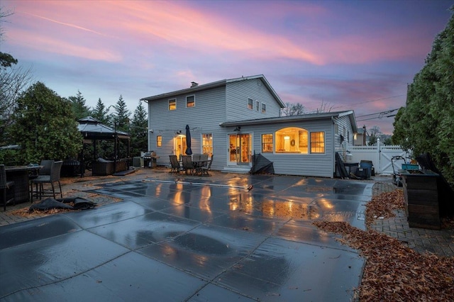 back house at dusk with a gazebo and a patio