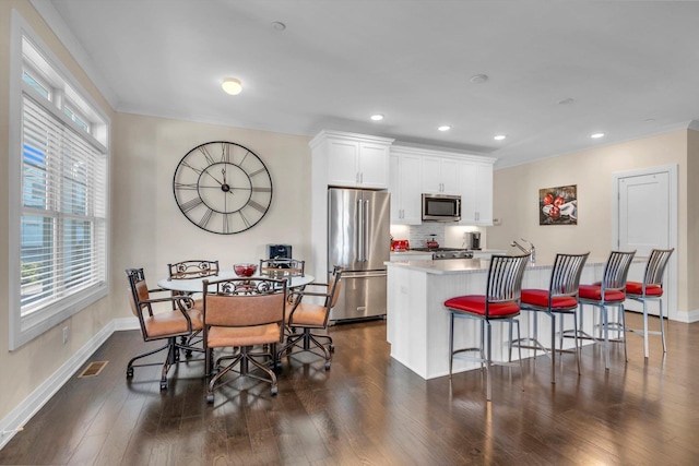 kitchen with white cabinetry, a kitchen island with sink, dark hardwood / wood-style floors, and appliances with stainless steel finishes