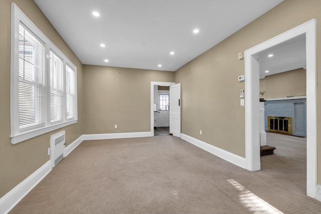 empty room with light colored carpet and a brick fireplace