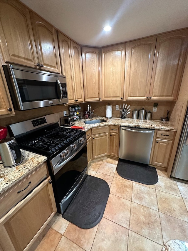 kitchen featuring sink, light stone countertops, stainless steel appliances, and light tile patterned floors