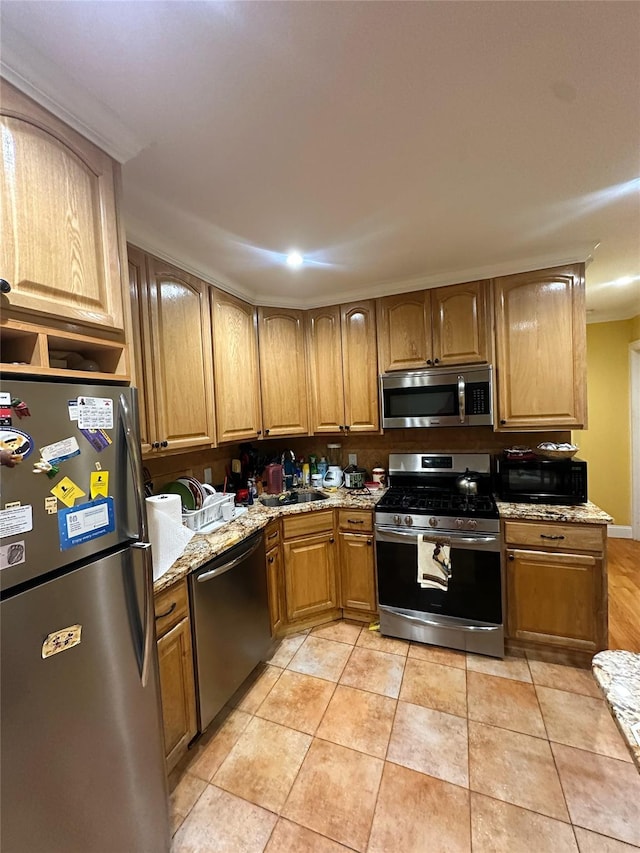 kitchen featuring light stone counters, sink, light tile patterned floors, and stainless steel appliances