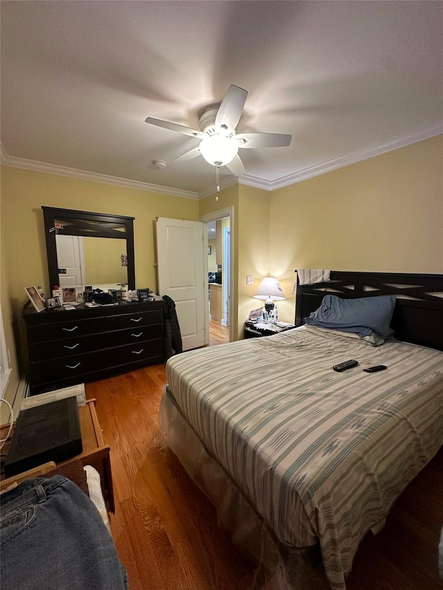 bedroom featuring ceiling fan, wood-type flooring, and ornamental molding