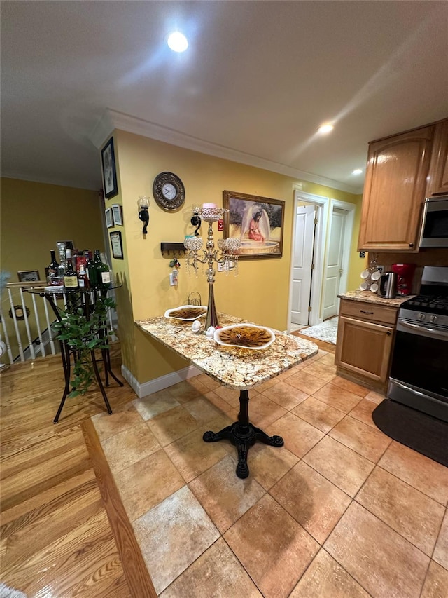 kitchen featuring light stone counters, light tile patterned floors, stainless steel appliances, and ornamental molding