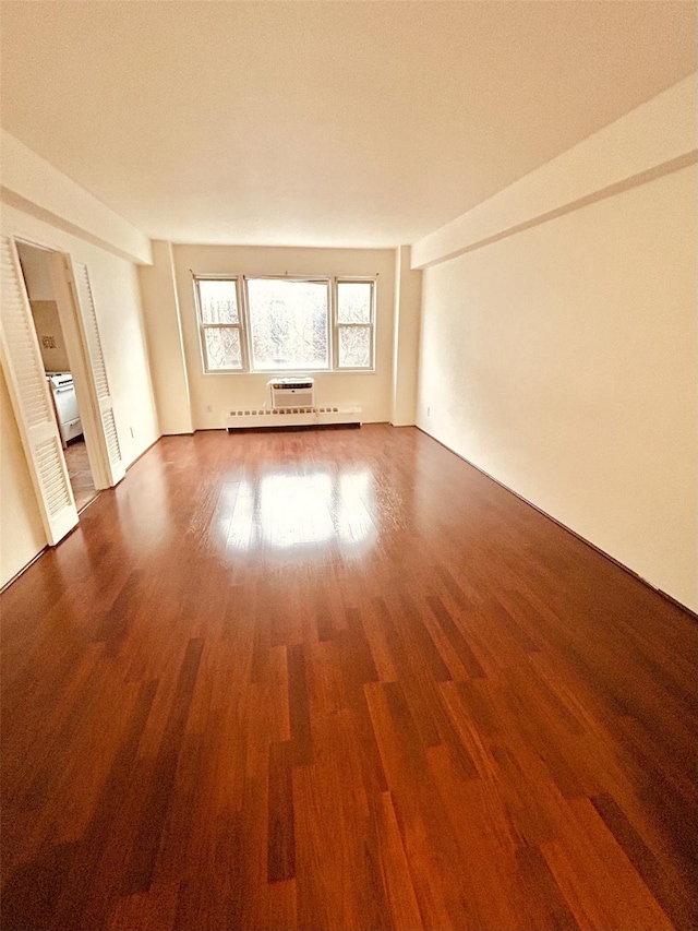 unfurnished room featuring hardwood / wood-style flooring and a baseboard heating unit