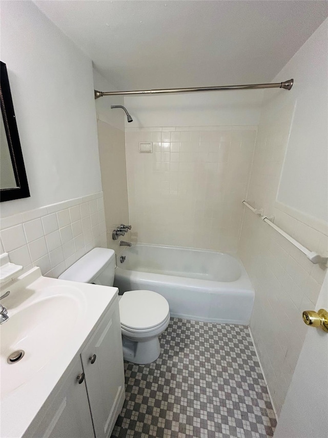 full bathroom with vanity, toilet, tile walls, and tiled shower / bath combo