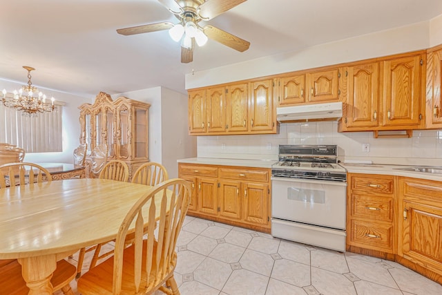 kitchen featuring ceiling fan with notable chandelier, white range, decorative backsplash, decorative light fixtures, and light tile patterned flooring