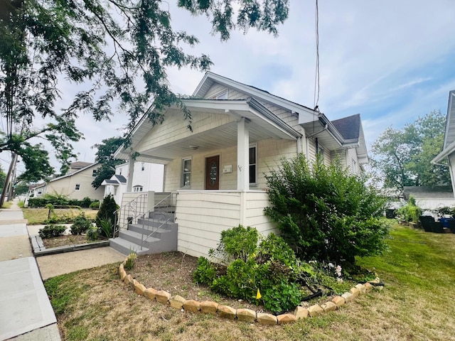 view of side of home featuring a yard and covered porch