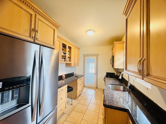 kitchen featuring light tile patterned flooring, sink, appliances with stainless steel finishes, and dark stone counters