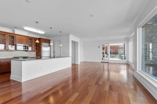 kitchen with pendant lighting, stainless steel appliances, hardwood / wood-style flooring, and ornamental molding