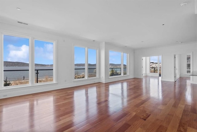 unfurnished living room featuring hardwood / wood-style floors and a water view